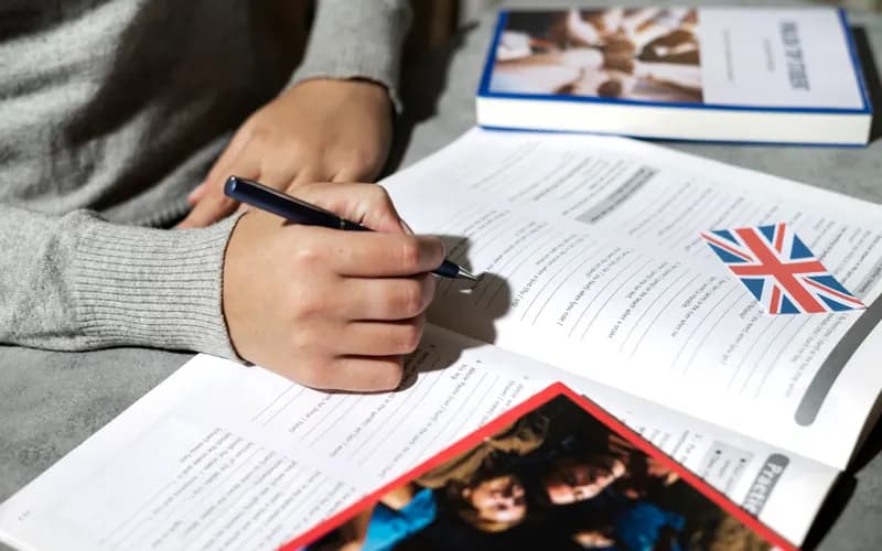 Estudante escrevendo em um material didático de língua inglesa